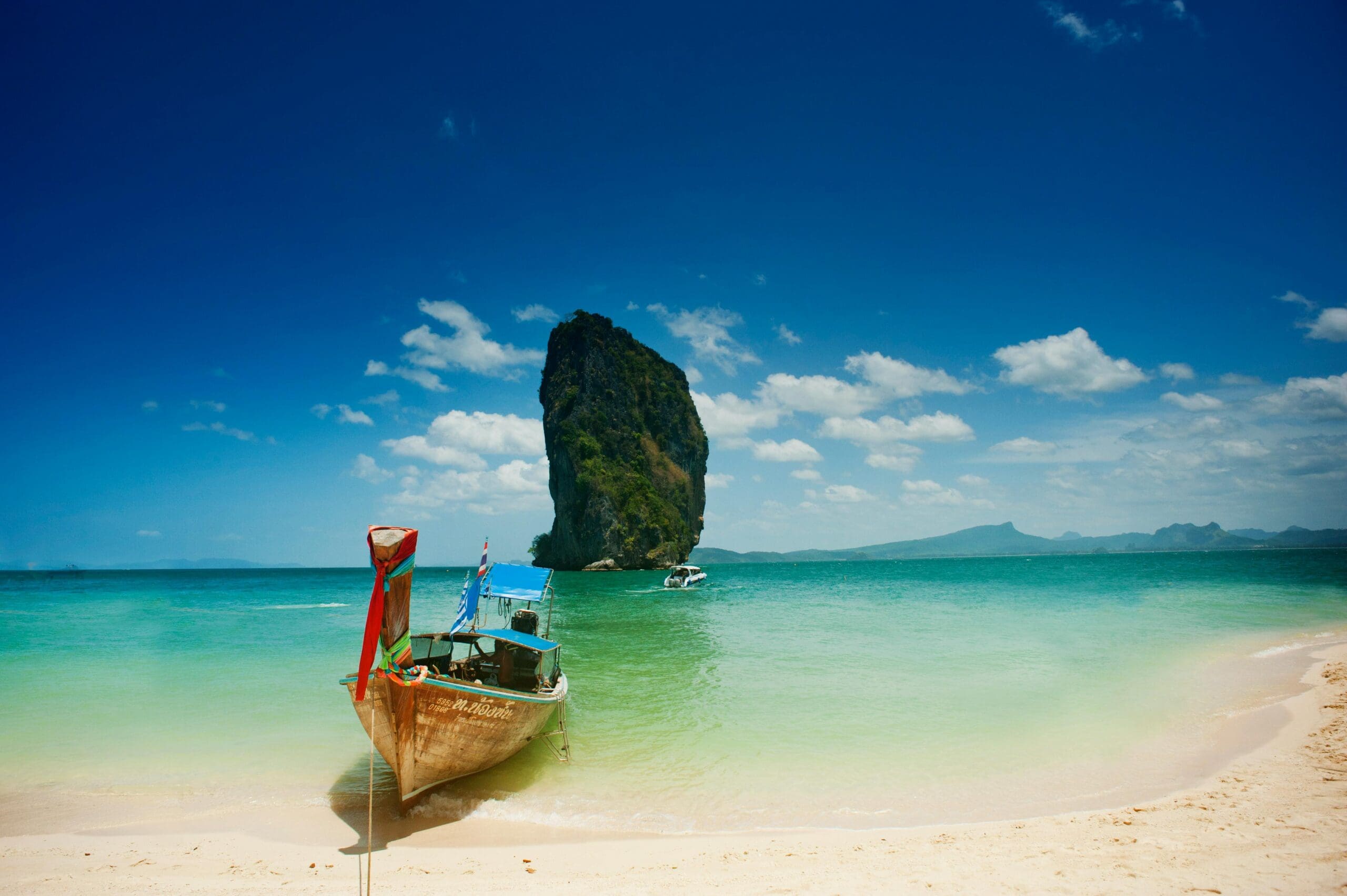 boat pulled up on exotic island beach with a passenger with thai elite visa